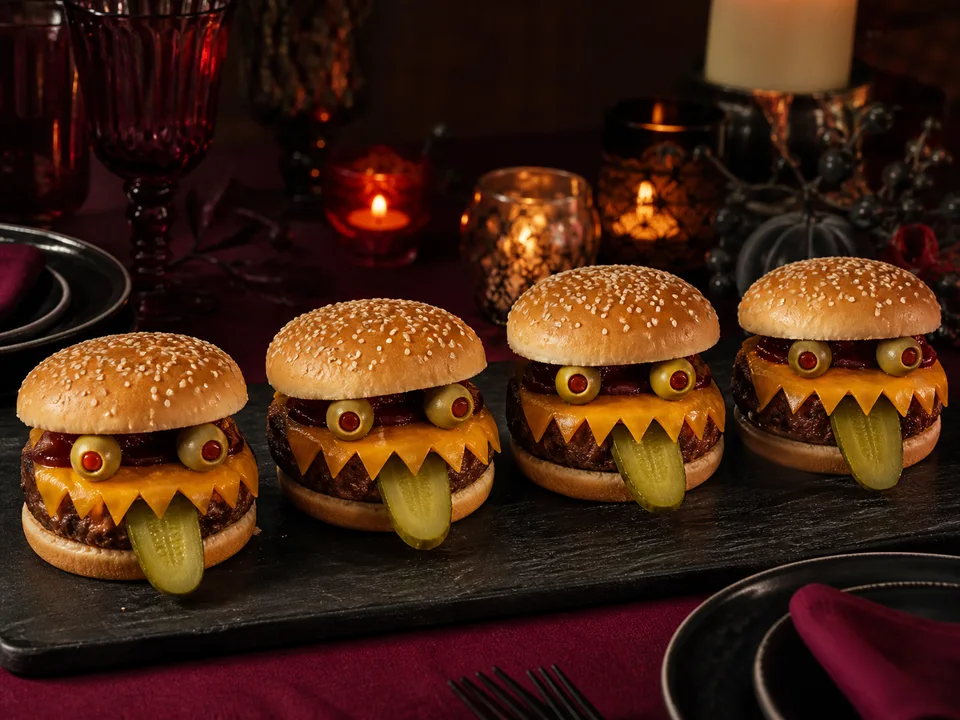 Vier goldbraune Monster-Burger auf einem dunklen Servierbrett